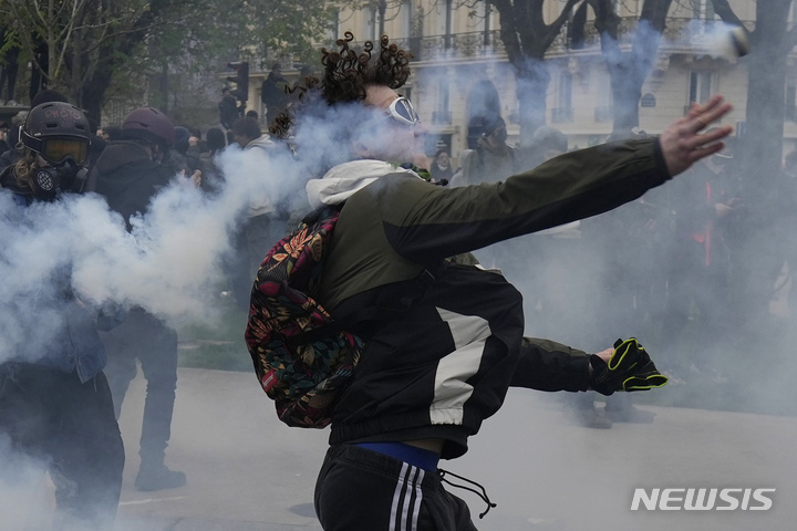 [파리=AP/뉴시스] 28일(현지시간) 프랑스 파리에서 연금 개혁 반대 시위를 벌이던 남성이 경찰이 쏜 최루탄을 되던지고 있다. 프랑스 전역에서 에마뉘엘 마크롱 정부의 연금 개혁에 반대하는 10차 시위와 파업이 이어졌다. 마크롱 대통령은 인기를 잃더라도 국익을 위해 연금 개혁을 흔들림 없이 추진하겠다고 밝혔다. 2023.03.29.