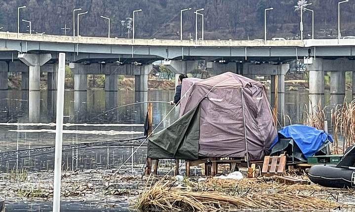 [대구=뉴시스] 정재익 기자 = 대구시 북구 동변동 금호강 산격대교 인근 고수부지 일대에 설치된 불법 텐트에서 한 사람이 낚시를 하고 있다. 2023.03.29. jjikk@newsis.com *재판매 및 DB 금지