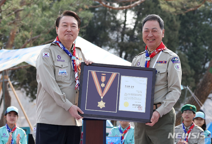 [서울=뉴시스] 홍효식 기자 = 윤석열 대통령이 29일 오후 서울 용산 대통령실 파인그라스 정원에서 열린 한국스카우트연맹 명예총재 추대식에서 강태선 총재로부터 스카우트 최고 훈장인 무궁화 금장을 받고 있다. (대통령실통신사진기자단) 2023.03.29. yesphoto@newsis.com