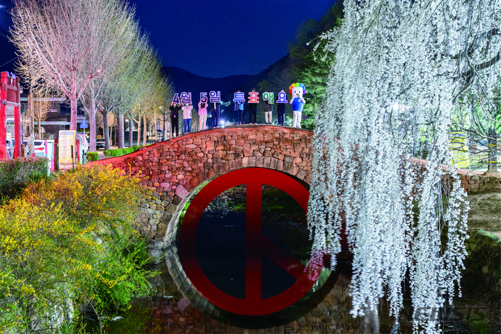 [창녕=뉴시스] 홍정명 기자=경남도선관위와 창녕군선관위 직원들이 지난 1일 밤 8시 창녕군 영산면 소재 만년교(다리 아래쪽 원형에 기표 모양 편집)에서 벚꽃을 배경으로 오는 4월 5일 실시하는 창녕군수 등 보궐선거 투표 독려 퍼포먼스를 펼치고 있다.(사진=경남선관위 제공) 2023.04.02. photo@newsis.com