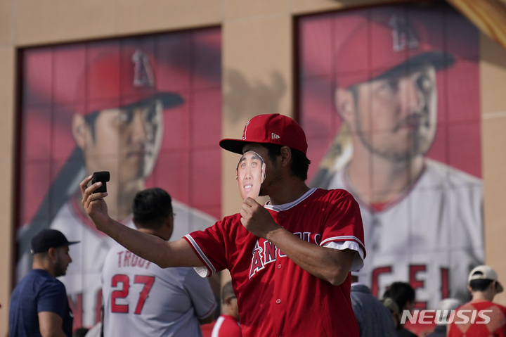 [로스앤젤레스=AP/뉴시스]오타니 쇼헤이가 10일(한국시간) LA 다저스와 계약을 발표했다. 원 소속팀이던 에인절스는 구장에 붙어있던 오타니 벽화를 철거했다. 사진은 지난 4월12일 에인절스타디움에서 열린 워싱턴 내셔널스와 LA 에인절스 경기를 앞두고 한 팬이 오타니 쇼헤이 가면을 쓰고 사진을 찍고 있는 모습. 2023.12.10.