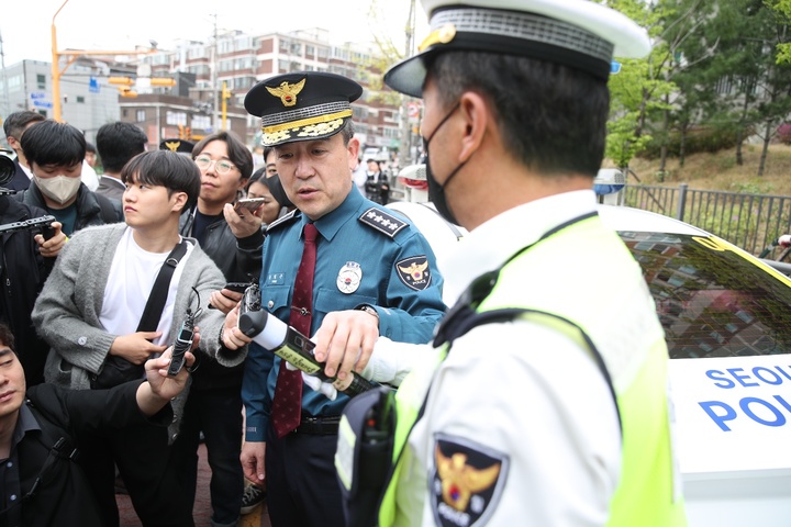 윤희근 경찰청장이 서울 서대문구의 한 초등학교 앞에서 진행한 낮 음주운전 단속 현장을 찾아 신형 음주측정기 사용법을 듣고 있다. 사진=경찰청 제공 *재판매 및 DB 금지