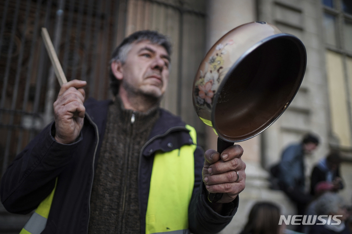 [리옹=AP/뉴시스] 에마뉘엘 마크롱 프랑스 대통령이 17일(현지시간) 연금 개혁과 관련해 TV 대국민 연설을 하는 동안 리옹에서 시위대가 냄비를 두드리고 있다. 마크롱 대통령은 정년을 62세에서 64세로 올린 데 대한 국민의 분노를 들었다면서도 이는 필요한 개혁이었다고 말했다. 이에 프랑스 8개 주요 노조는 "대통령이 여전히 국민의 분노를 이해하지 못하고 있다"라며 "5월 1일 프랑스 전역에서 국민의 진짜 분노를 들려주겠다"라고 경고했다. 2023.04.18.