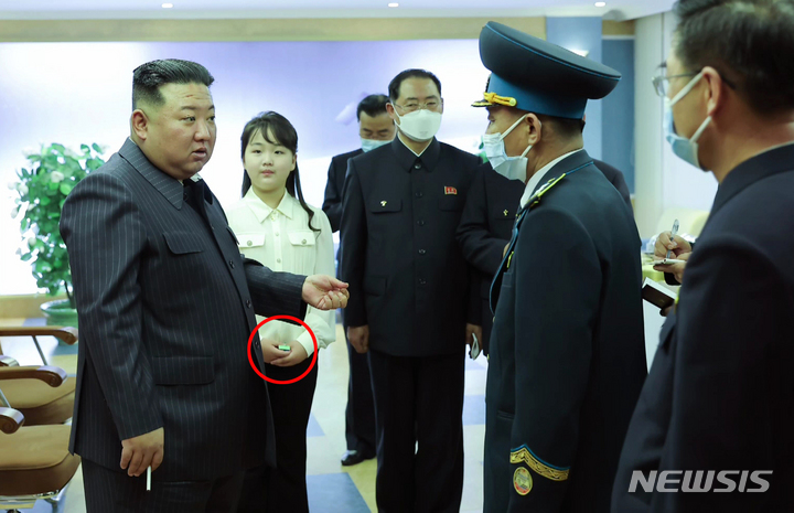 [서울=뉴시스] 북한 조선중앙TV가 19일 공개한 18일 김정은 국무위원장의 우주과학연구원 방문 모습에서 김 위원장의 딸 김주애가 두손으로 성냥갑을 든 장면이 포착됐다. 이는 김 위원장 독재 체제의 위상을 나타내며, 김 위원장이 시찰 현장에서 담배를 피우는 것은 그의 조부 김일성이 과거 현장에서 담배를 들고 보고를 받던 모습을 흉내낸 것이라는 분석이다. (사진=조선중앙TV 캡쳐) 2023.04.19. photo@newsis.com