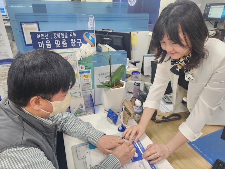 20일 서울 소재 신한은행 영업점 행원(오른쪽)이 응대 키트를 활용해 시각장애인 고객의 업무를 돕고 있다. (사진=신한은행 제공) *재판매 및 DB 금지