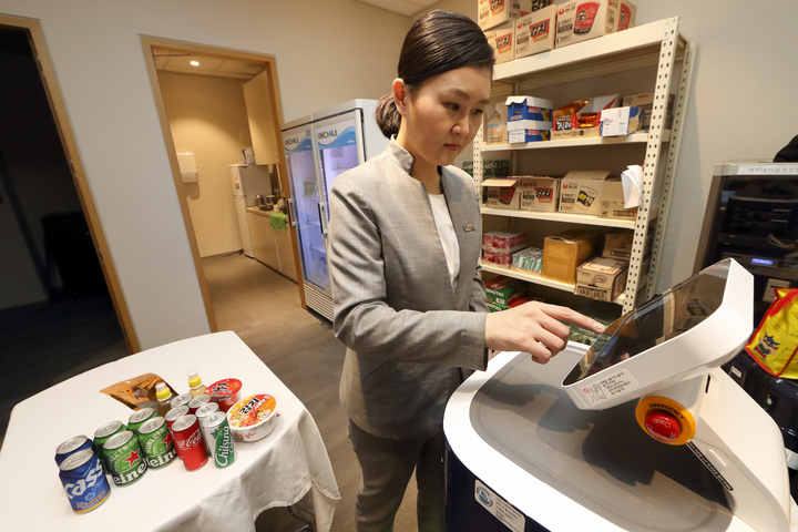 [제주=뉴시스] KT는 최근 제주신화월드에 AI 실내배송로봇 '똣똣' 5대를 도입했다. 사진은 투숙객이 주문한 편의점 물품을 호텔리어가 '똣똣'에 넣어 배송하는 모습. (사진=KT 제공) *재판매 및 DB 금지