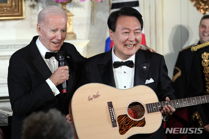 [워싱턴=AP/뉴시스] 윤석열 대통령이 26일(현지시간) 백악관에서 열린 국빈 만찬을 마친 후 조 바이든 대통령으로부터 미국 싱어송라이터 돈 맥클린의 친필 서명이 담긴 기타를 선물받고 있다. 2023.04.27.