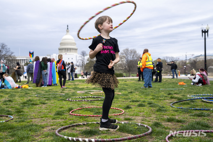 [워싱턴=AP/뉴시스] 사진은 '국제 트랜스젠더 가시화의 날'인 지난달 31일(현지시간) 미 워싱턴의 국회의사당 앞에서 6세 소년이 '논바이너리' 동생을 응원하며 훌라후프를 돌리고 있는 모습. 2023.04.28. *재판매 및 DB 금지
