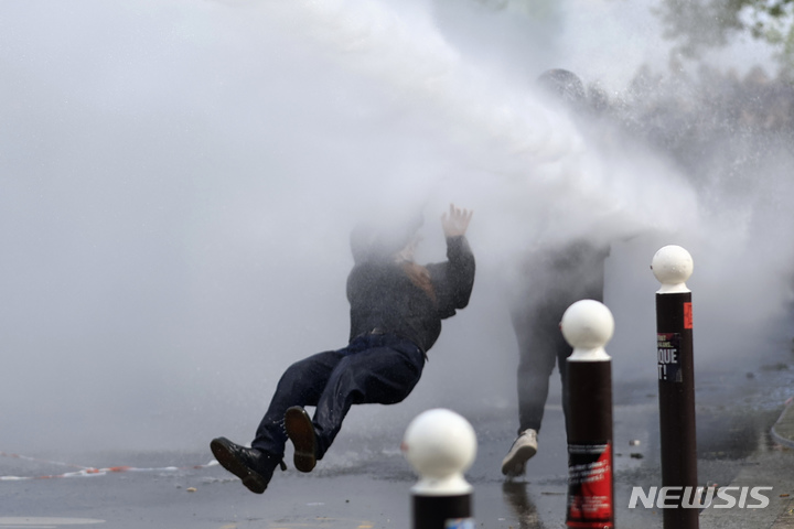 [파리=AP/뉴시스] 1일(현지시간) 프랑스 파리에서 노동절을 맞아 열린 연금개혁 반대 시위에서 한 참가자가 경찰이 쏜 물대포에 맞아 쓰러지고 있다. 2023.05.02.