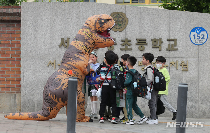 [서울=뉴시스] 권창회 기자 = 어린이날을 하루 앞둔 4일 오후 서울 마포구 한 초등학교 앞에서 공룡분장을 한 시민이 어린이들에게 사탕을 나눠주고 있다. 2023.05.04. kch0523@newsis.com