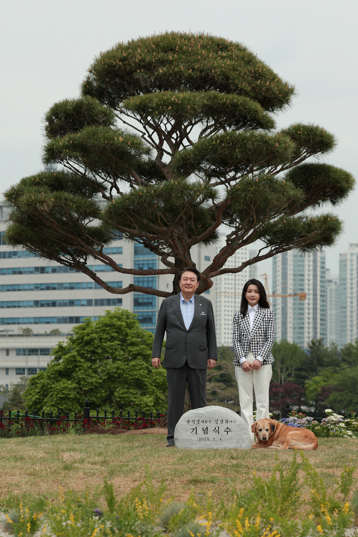 [서울=뉴시스] 윤석열 대통령과 부인 김건희 여사가 4일 서울 용산 대통령실 앞 미군기지 반환부지에 조성된 용산어린이정원 내 전망언덕에서 기념식수를 마친 뒤 은퇴 안내견 새롬이와 기념촬영하고 있다. (사진=대통령실 제공) 2023.05.04. photo@newsis.com *재판매 및 DB 금지