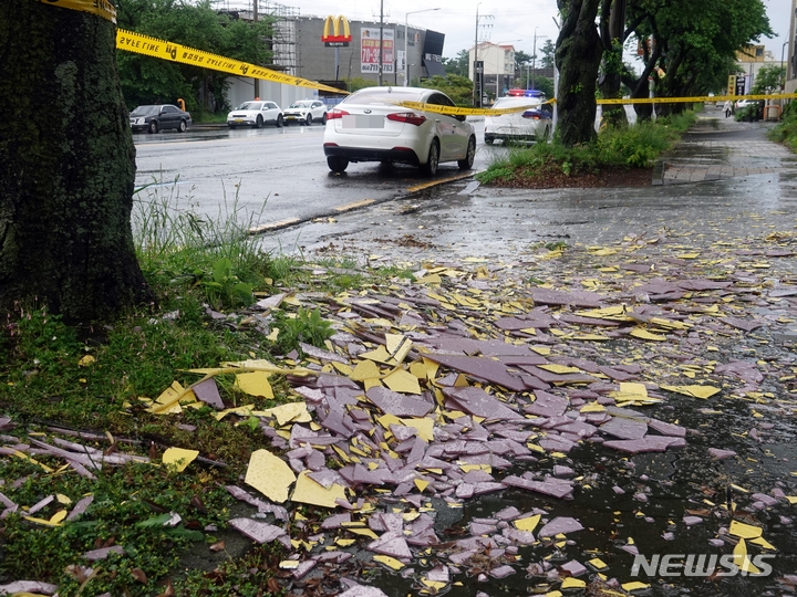 [제주=뉴시스] 오영재 기자 = 강풍을 동반한 많은 비가 내리고 있는 5일 오전 제주시 연동의 한 건물 외벽 타일이 강풍에 의해 도로에 떨어져 통제가 이뤄지고 있다. 2023.05.05. oyj4343@newsis.com 