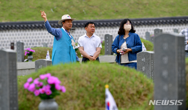 [광주=뉴시스] 이영주 기자 = 12일 오후 광주 북구 운정동 국립5·18민주묘지에서 참배객들이 해설사로부터 묘역 관련 설명을 듣고 있다. 2023.05.12. leeyj2578@newsis.com