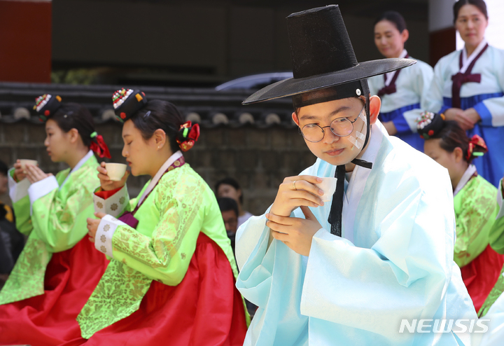 [서울=뉴시스] 최진석 기자 = 지난 2023년 5월14일 오후 서울 중구 덕수궁 돌담길에서 열린 '전통 성년례'에서 올해 성년을 맞은 학생들이 술을 마시는 의식인 초례를 하고 있는 모습. 2023.05.14. myjs@newsis.com
