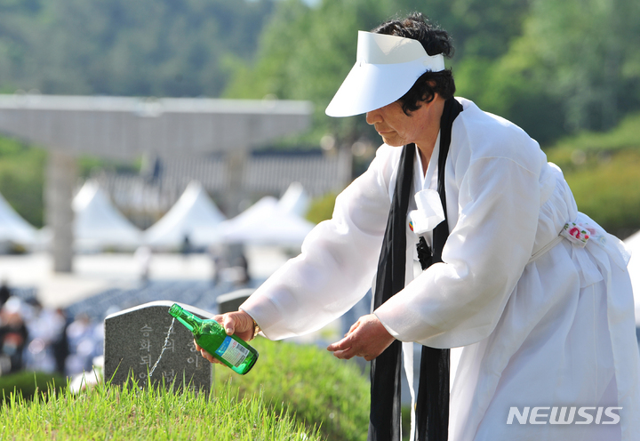 [광주=뉴시스] 이영주 기자 = 5·18민주화운동 43주기를 하루 앞둔 17일 오전 광주 북구 운정동 국립5·18민주묘지에서 고(故) 임수춘 열사의 아내 윤삼례 여사가 남편의 묘소에 소주를 붓고 있다. 2023.05.17. leeyj2578@newsis.com