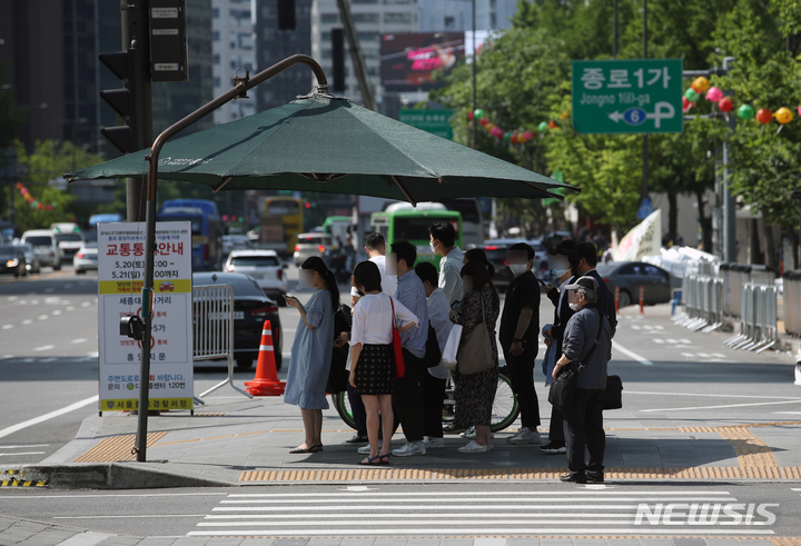 [서울=뉴시스] 고승민 기자 = 한낮 무더위가 예고된 17일 서울 광화문 사거리 그늘막에서 시민들이 횡단보도 신호를 기다리고 있다. 2023.05.17. kkssmm99@newsis.com