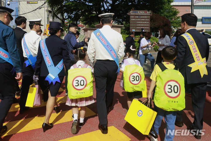 [서울=뉴시스] 최동준 기자 = 윤희근 경찰청장이 지난 5월17일 서울 구로구 덕의초등학교 앞에서 어린이들에게 교통안전 가방 덮개를 씌어준 뒤 함께 학교로 들어가고 있다. 2023.05.17. photocdj@newsis.com