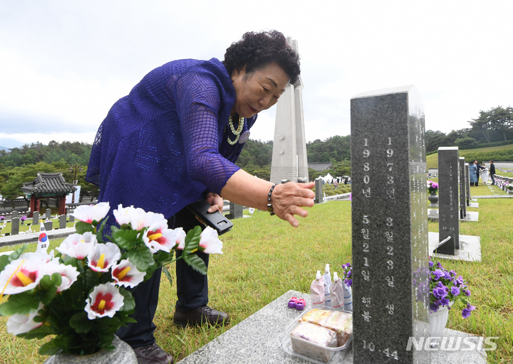 [광주=뉴시스] 김혜인 기자 = 18일 오전 광주 북구 운정동 국립 5·18민주묘지 행방불명자 묘역에서 이창현군의 어머니가 아들의 사진을 만지고 있다. 1980년 5월 당시 7살이었던 이 군은 현재까지 행적이 알려지지 않고 있다. 2023.05.18.hyein0342@newsis.com