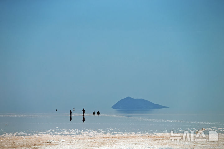 [우르미아( 이란)=AP/뉴시스] 기후 변화로 수위가 대폭 낮아진 이란의 우르미아 해변에서 사람들이 수영대신 산책을 하고 있는 모습. 이란 환경부는 아프가니스탄 국경지대의 하문호수와 습지가 사라져간다며 강 상류지역인 아프간의 탈레반 정부에 이를 되살리는 작업에 동참해 달라고 26일(현지시간) 요청했다. 2023.07.27. 