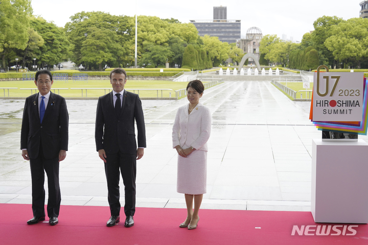 [히로시마=AP/뉴시스]19일 주요 7개국(G7) 정상회의가 일본 히로시마에서 개막했다. 기시다 후미오 일본 총리 부부가 히로시마 평화기념공원에서 에마뉘엘 마크롱 프랑스 대통령을 맞이해 함께 기념 촬영을 하고 있다. 왼쪽부터 기시다 총리, 마크롱 대토열ㅇ, 기시다 유코 여사. 2023.05.19.