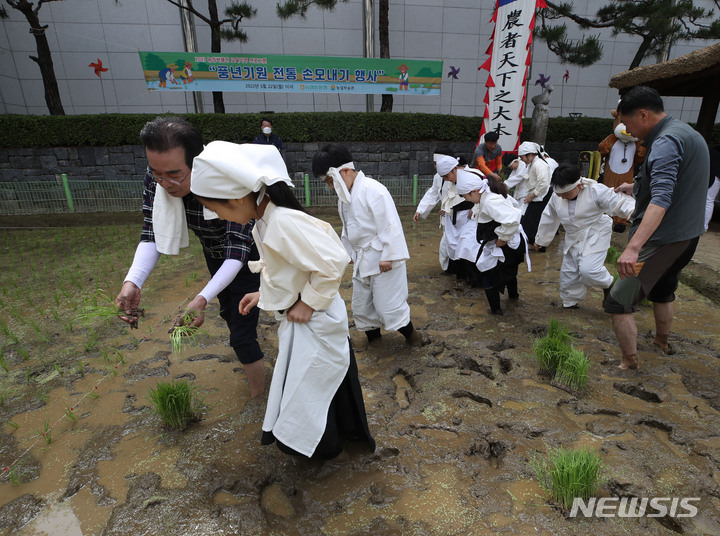 [서울=뉴시스] 조수정 기자 = 22일 오전 서울 중구 농협 농업박물관 야외체험농장에서 이성희 농협중앙회장과 미동초등학교 3학년 학생들이 못줄을 사용한 전통 손모내기 체험을 하고 있다. 2023.05.22. chocrystal@newsis.com