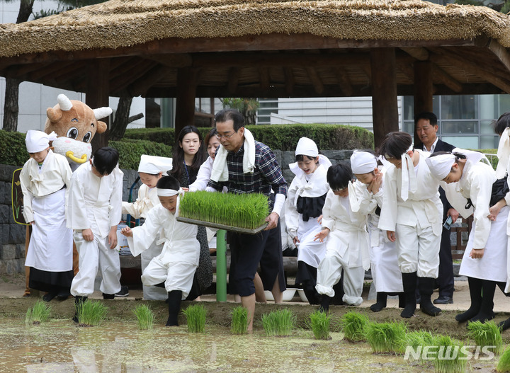 [서울=뉴시스] 조수정 기자 = 22일 오전 서울 중구 농협 농업박물관 야외체험농장에서 이성희 농협중앙회장과 미동초등학교 3학년 학생들이 못줄을 사용한 전통 손모내기 체험을 하고 있다. 2023.05.22. chocrystal@newsis.com