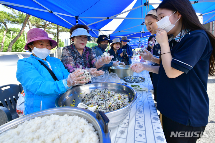 [광주=뉴시스] 이영주 기자 = 23일 오후 광주 남구 효천역에서 5·18민주화운동 제43주기를 맞아 열린 2023 송암·효천 5·18추모문화제 도중 효천중학교 학생들과 지역 주민들이 주먹밥을 나누고 있다. 2023.05.23.leeyj2578@newsis.com