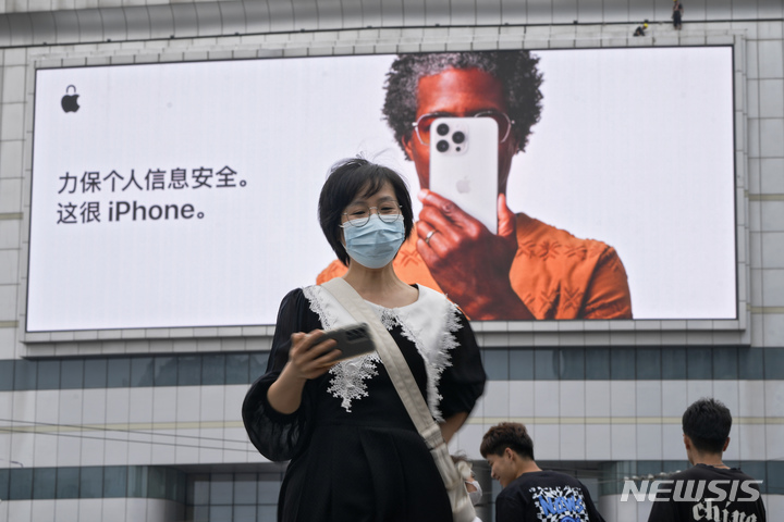[베이징=AP/뉴시스] 중국 규제당국이 18세 미만 청소년의 스마트폰 사용 시간을 하루 최대 2시간으로 제한하는 법안의 초안을 공개했다고 3일(현지시간) 미국 NBC는 보도했다. 사진은 아이폰 광고가 표시된 대형 스크린을 지나가는 중국 시민. 2023.08.03. 