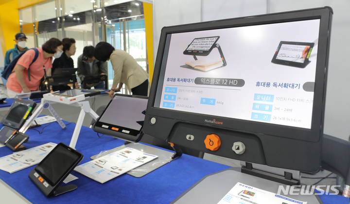 [서울=뉴시스] 김금보 기자 = 26일 서울 서초구 aT센터에서 열린 '대한민국 보조공학기기 박람회'에서 관람객들이 독서확대기을 살펴보고 있다. 2023.05.26. kgb@newsis.com