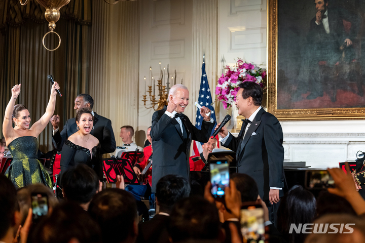 [서울=뉴시스]대통령실은 27일 윤석열 정부 출범 1주년을 기념해 '국민과 함께 시작한 여정'이라는 제목이 사진집을 냈다. 미국 국빈 방문 공식 만찬 당시 '아메리칸 파이' 열창 후 조 바이든 대통령 등 관계자들과의 모습. 대통령실 제공