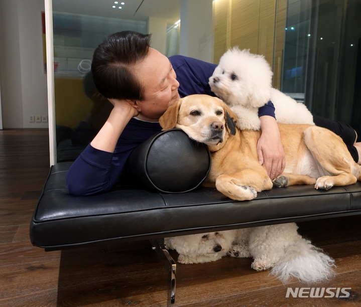 [서울=뉴시스]대통령실은 27일 윤석열 정부 출범 1주년을 기념해 '국민과 함께 시작한 여정'이라는 제목이 사진집을 냈다. 윤 대통령이 반려견들과 함께 지내는 모습. 대통령실 제공