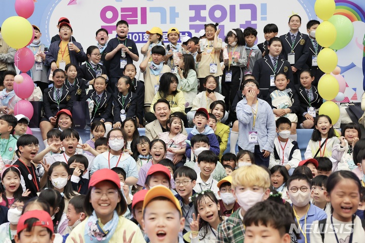 [서울=뉴시스]대통령실은 27일 윤석열 정부 출범 1주년을 기념해 '국민과 함께 시작한 여정'이라는 제목이 사진집을 냈다. 어린이날 행사에 참석해 어린이들과 포즈를 취하고 있는 윤 대통령 부부. 대통령실 제공