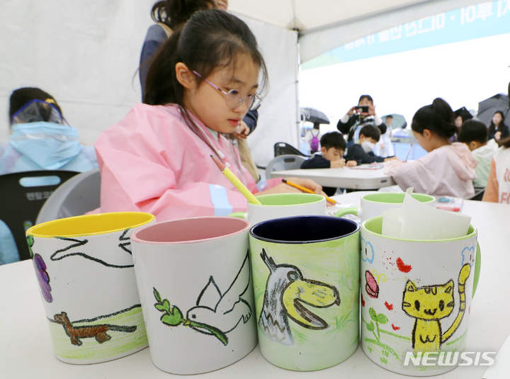 [김포=뉴시스] 최진석 기자 = 27일 경기 김포 고촌읍 아라마리나 일원에서 열린 '2023 김포 아라마린 페스티벌'에서 어린이들이 머그컵 만들기에 들어갈 그림을 그리고 있다.&nbsp;&nbsp; 올해로 제 7회를 맞이한 김포와 아라뱃길의 대표축제인 '2023년 김포 아라마린 페스티벌'은 수상·수변 인프라를 활용한 수상레저체험(요/보트, 카약, 수상자전거, SUP), 덕레이스 등 다채로운 수상 이벤트와 다양한 초대가수들이 함께하는 문화콘서트, 그리고 물, 환경을 주제로 한 체험과 이벤트가 가득한 행사로 이날부터 28일까지 양일간 진행된다. 2023.05.27. myjs@newsis.com