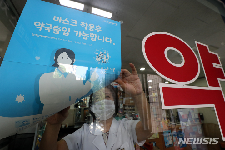 한 약국에서 약사가 마스크 착용 안내문을 떼고 있다. 2023.05.31. kmn@newsis.com