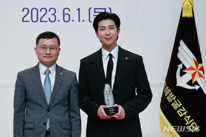 [서울=뉴시스] 사진공동취재단 = 방탄소년단(BTS)의 RM(김남준)이 1일 서울 동작구 국립서울현충원 현충관에서 열린 국방부 유해발굴감식단 홍보대사 위촉식에 참석해 이근원 단장으로부터 위촉패를 수여받은 뒤 기념 촬영하고 있다. 2023.06.01. photo@newsis.com