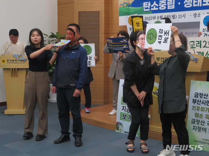 [부산=뉴시스] 이동민 기자 = 5일 오전 부산시의회 브리핑룸에서 부산 환경단체들이 세계 환경의 날을 기념해 연 기자회견에서 박형준 부산시장과 윤석열 대통령 얼굴이 그려진 가면을 쓴 활동가들에게 각각 녹조 와 방사능 마크가 붙여진 물고기를 먹이는 퍼포먼스를 선보이고 있다. 2023.06.05. eastsky@newsis.com