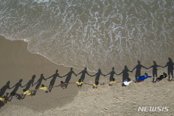 [리우데자네이루=AP/뉴시스] 세계 해양의 날인 8일(현지시각) 브라질 리우데자네이루 해변에서 사람들이 '바다를 안아주자'는 상징적인 의미로 서로 손을 잡고 인간 띠를 만들고 있다. 루트 브라질이라는 환경단체는 해양 오염에 대한 사람들의 관심을 높이기 위해 '댓 허그'(That Hug) 행사를 열고 사람들의 참가를 촉구했다. 2023.06.09. 