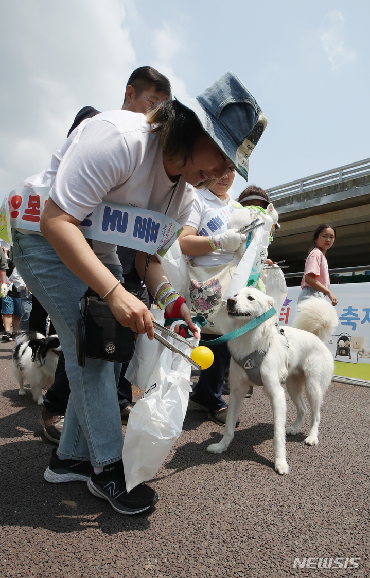 [서울=뉴시스] 고승민 기자 = 11일 서울 서초구 매헌시민의숲 반려견놀이터에서 열린 '반려견 놀이터 개장 축제'를 찾은 시민들이 인근 산책로를 따라 반려견과 플로깅 캠페인을 하고 있다. 2023.06.11. kkssmm99@newsis.com