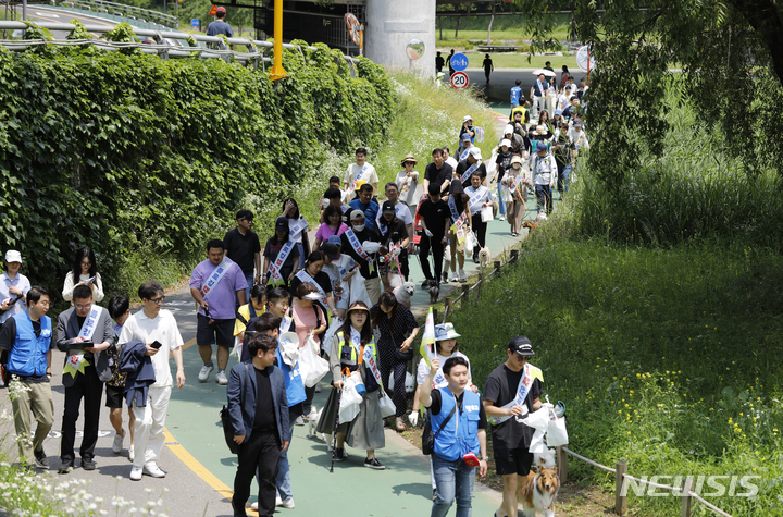 [서울=뉴시스] 고승민 기자 = 11일 서울 서초구 매헌시민의숲 반려견놀이터에서 열린 '반려견 놀이터 개장 축제'를 찾은 시민들이 인근 산책로를 걸으며 반려견과 플로깅 캠페인을 하고 있다. 2023.06.11. kkssmm99@newsis.com