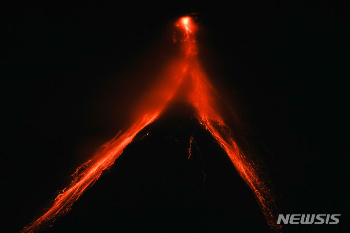 [레가스피(필리핀)=AP/뉴시스]필리핀 북동부 알베이주의 레가스피에서 12일 밤 마욘 화산에서 분출된 용암이 흘러내리는 모습이 선명하게 보이고 있다. 마욘 화산 폭발에 대한 두려움으로 인근 마을 주민들 약 1만5000명이 13일 트럭을 이용 대피에 나섰다. 마욘 화산은 지난주부터 화산 활동이 급격히 증가, 시뻘건 용암을 흘려보내고 화산재도 분출하고 있다. 2023.06.13.