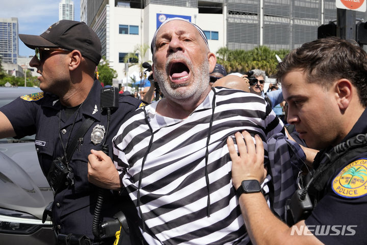[마이애미=AP/뉴시스] 13일(현지시각) 미 플로리다주 마이애미 연방 법원 앞에서 죄수복을 입은 채 도널드 트럼프 전 대통령을 구속하라고 외치던 한 남성이 경찰에 연행되고 있다. 불법 기밀 반출 등의 혐의로 기소된 트럼프 전 대통령은 이날 마이애미 연방 법원에 출석했다. 2023.06.14.
