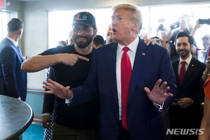 [마이애미=AP/뉴시스]도널드 트럼프 전 미국 대통령이 13일(현지시간) 플로리다 마이애미 법원에서 문건 유출 관련 기소인부 절차를 마친 뒤 인근 쿠바 레스토랑에 들른 모습. 옆에서 지지자가 트럼프 전 대통령을 가리키고 있다. 2023.06.13.