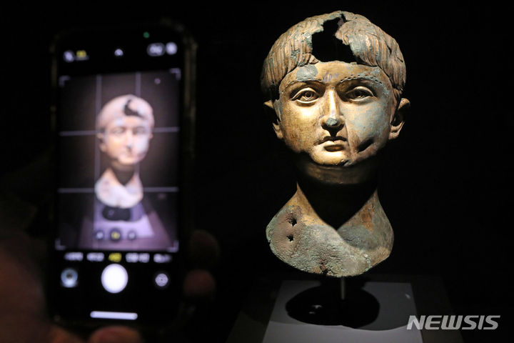 [서울=뉴시스] 박진희 기자 = '소년의 초상' 청동 두상. 금도금을 한 소년의 청동 두상으로, 지금은 남아 있지 않은 몸체에 끼워 본래 하나의 전신상을 구성했을 것이다. 작은 입과 통통한 볼로 어린아이 같은 이목구비를 보여 준다. 머리 오른쪽 부분에는 '소년의 곱슬머리'라 불리는 형태가 보이는데, 이집트 문화권에서 온 이 머리모양은 아이들만 하는 것이었다. 값비싼 도 금은 소년이 왕자와 같이 사회적 지위가 높은 인물이었음을 드러낸다. 이마 부분이 왜 파손되었는지, 이 두상의 기능이 무엇이었는지는 현재 알 수 없지만 죽은 소년을 기리는 초상 조각이었을 가능성이 있다. 2023.06.17. pak7130@newsis.com