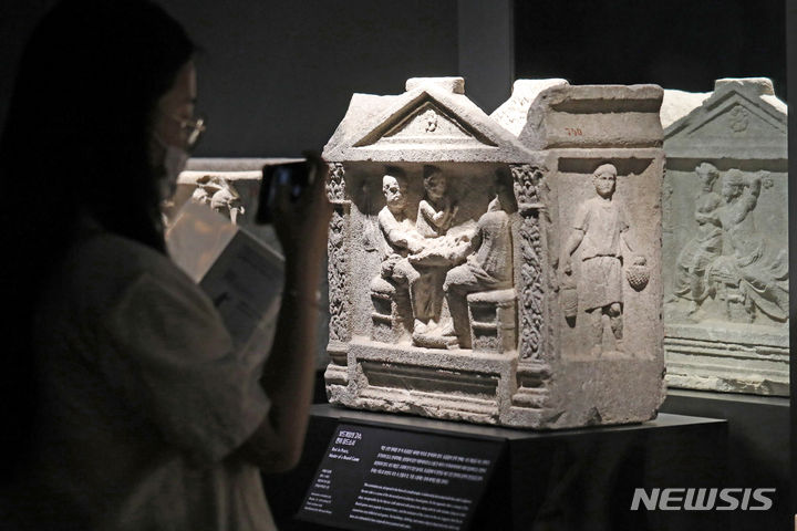 [서울=뉴시스] 박진희 기자 = '보드 게임의 고수, 편히 잠드소서' 석회암 유골함 부조. 작은 신전 형태를 한 이 유골함은 화려한 부조로 장식되어 있다. 양쪽 끝에는 넝쿨무늬 장식과 아칸서스 앞으로 장식한 모양이 특징인 코린토스식 주두가 있는 기둥을 표현했다. 한쪽 면에는 솔방울이 달린 지팡이 티르소스를 들고 아내 아리아드네와 함께 있는 바쿠스 신을 나타냈다. 이들은 상체가 드러난 제 침대에 누워 마주 보고 있다. 반대쪽에는 보드게임을 하는 망자를 조각했다. 보드게임은 고대에 인기 있던 놀이로, 유골함에 이 장면을 새긴 것은 망자의 실력이 좋았음을 보여주려는 의도일 수 있다. 2023.06.17. pak7130@newsis.com