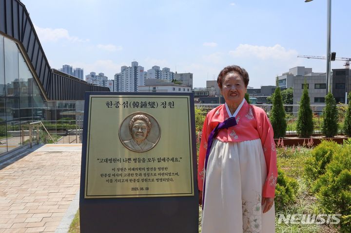 [서울=뉴시스]한종섭 할머니가 '한종섭 정원' 안내판 옆에 서서 기념 촬영을 하고 있다. (사진= 고려대의료원 제공) 2023.06.16. photo@newsis.com.