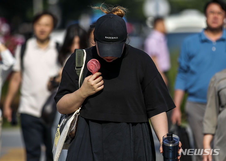 [서울=뉴시스] 정병혁 기자 = 19일 서울 종로구 광화문네거리에서 한 시민이 손선풍기로 더위를 피하며 이동하고 있다. 더운 날씨로 서울과 경기내륙, 강원영서중부, 전라권내륙 등 폭염특보가 발효됐으며, 기상청은 낮 최고기온이 35도까지 오를 것으로 예보했다. 2023.06.19. jhope@newsis.com