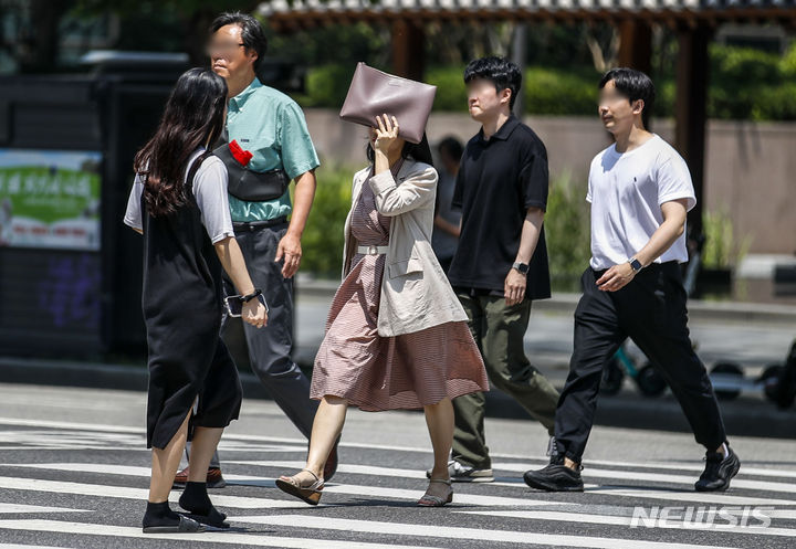 [서울=뉴시스] 정병혁 기자 = 서울 낮 최고 기온이 35도까지 오르는 등 더운 날씨를 보인 19일 서울 종로구 인근 교차로에서 햇빛을 가린 시민들이 이동하고 있는 모습. 2023.06.19. jhope@newsis.com