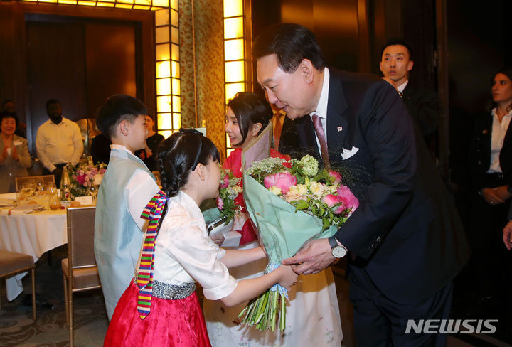 [파리=뉴시스] 홍효식 기자 = 윤석열 대통령과 부인 김건희 여사가 19일(현지시간) 파리 한 호텔에서 열린 프랑스 동포 초청 만찬 간담회에 입장하며 화동에게 꽃다발을 전달받고 있다. 2023.06.20. yesphoto@newsis.com