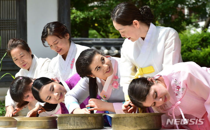 [경산=뉴시스] 이무열 기자 = 단오를 이틀 앞둔 20일 오전 경북 경산시 영남대학교 민속촌에서 외국인 유학생들이 한복을 곱게 차려입고 창포물에 머리를 감고 있다. 2023.06.20. lmy@newsis.com