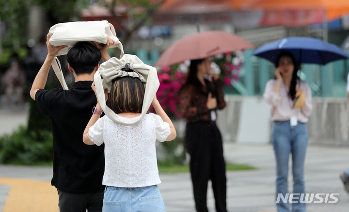 [서울=뉴시스] 김명년 기자 = 이번 주 토요일인 24일까지 전국이 대체로 맑은 날씨를 보이다 25일 일요일부터 전국이 장마철에 접어들기 시작하겠다. 사진은 지난 20일 오후 서울 광화문 사거리에서 시민들이 가방으로 머리를 가린 채 횡단보도를 건너고 있는 모습. 2023.06.20. kmn@newsis.com